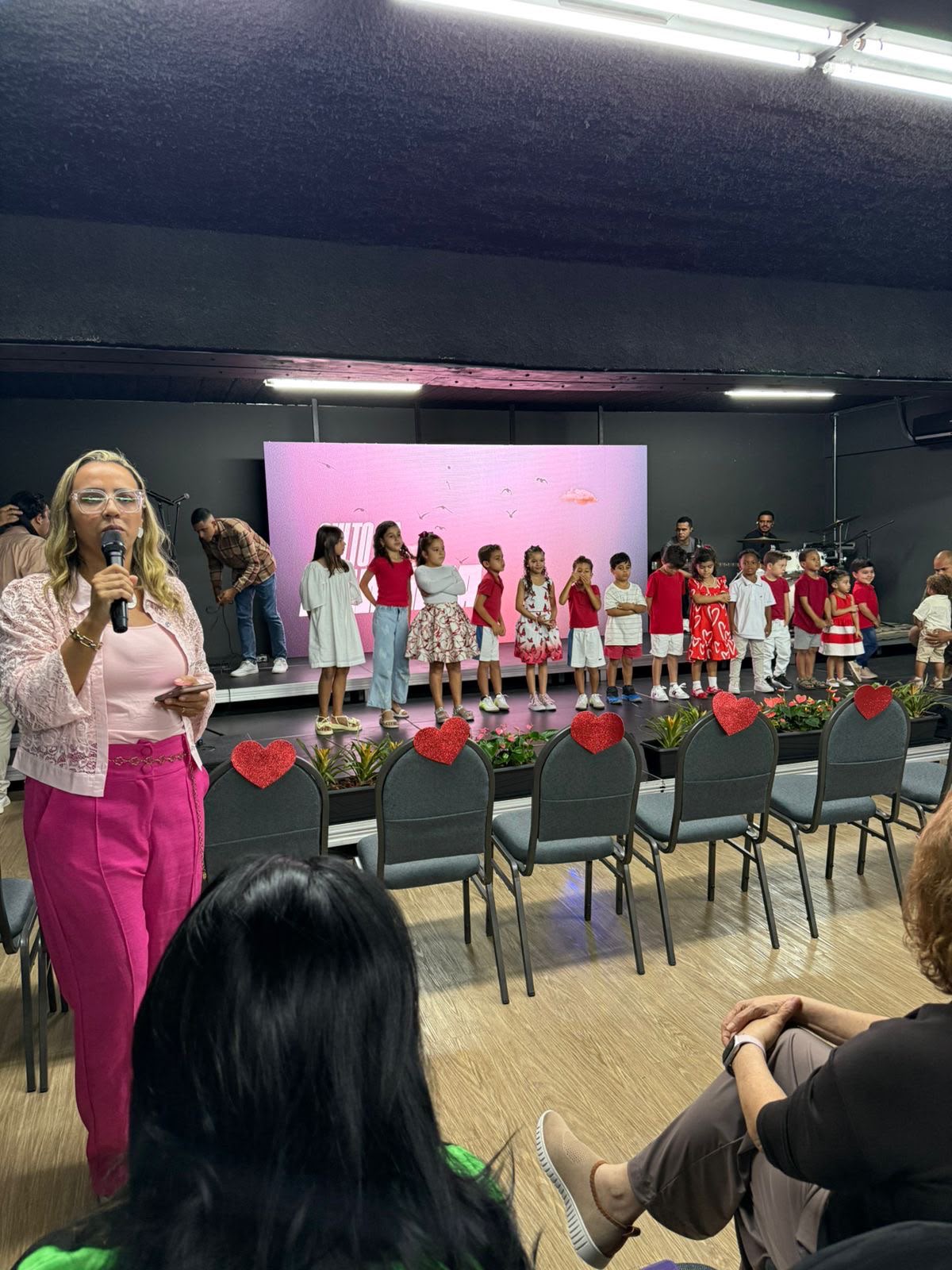 Raphaela Barros conduzindo evento com crianças no palco